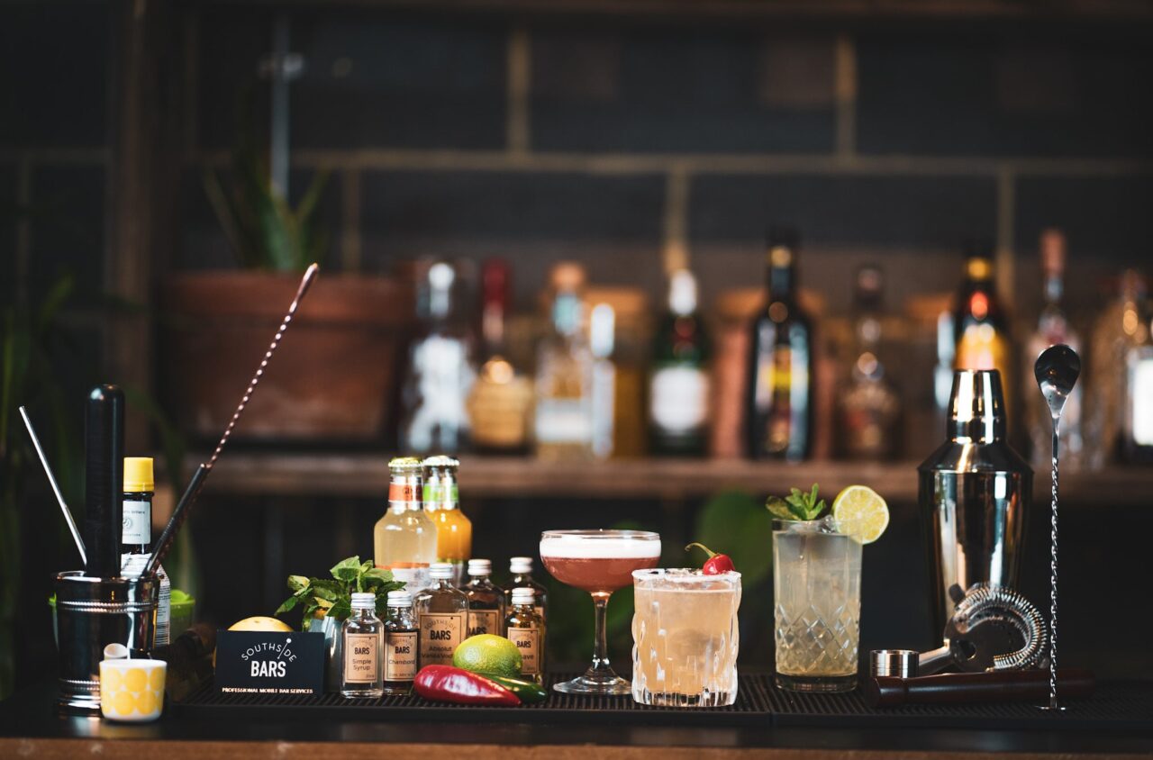 Cocktails and bar equipment set up on a bar.